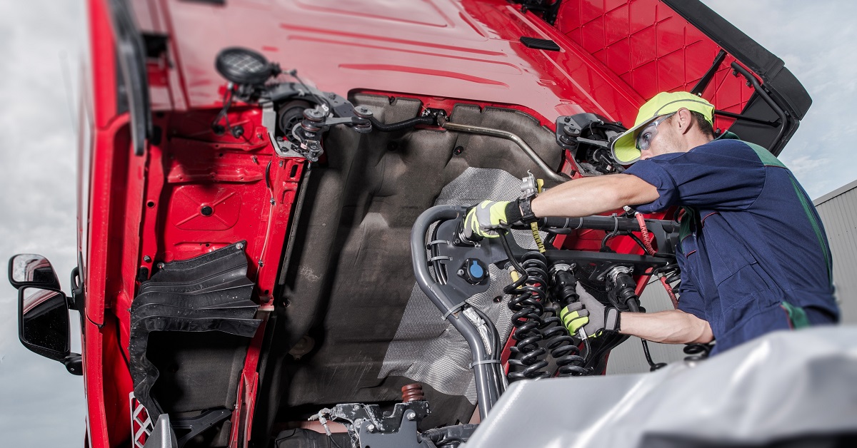 Semi Truck Under Maintenance. Caucasian Truck Mechanic Working to Fix the Tractor.